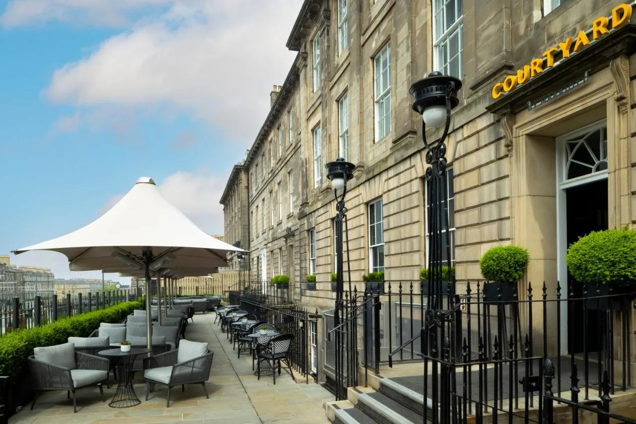 an outdoor patio with tables and chairs and an umbrella at Courtyard by Marriott Edinburgh in Edinburgh